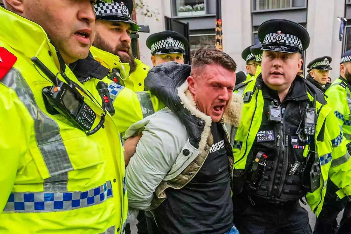 A man is arrested by several police officers wearing uniforms and reflective vests while showing an expression of anger or pain. A man is arrested by several police officers wearing uniforms and reflective vests while showing an expression of anger or pain.