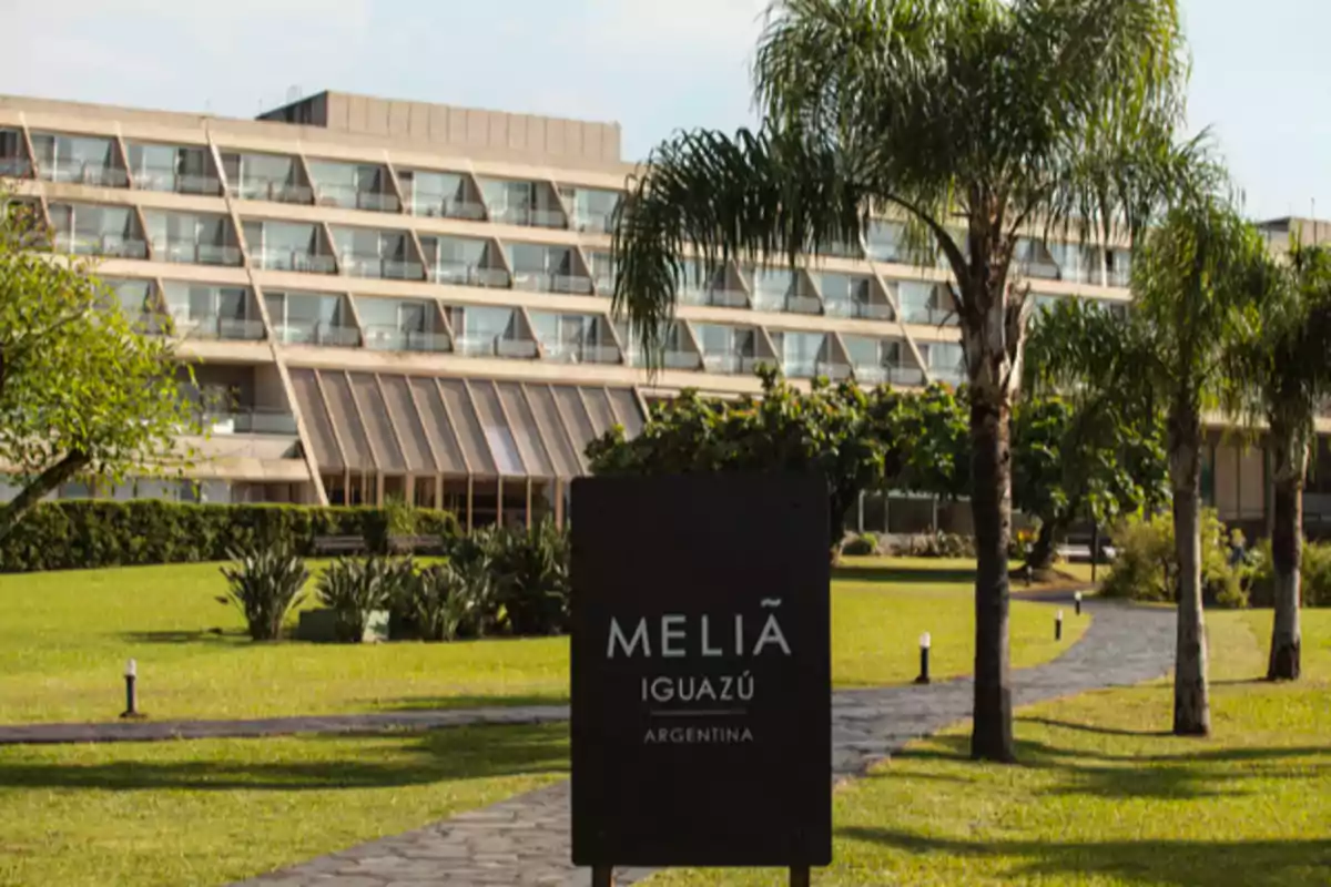 Edificio moderno rodeado de jardines con palmeras y un cartel que dice "Meliá Iguazú Argentina".