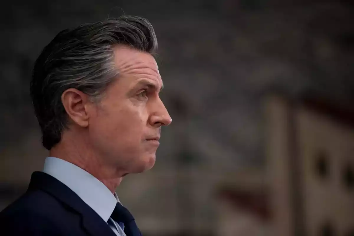 Hombre de perfil con cabello canoso y traje oscuro mirando hacia la derecha con expresión seria Hombre de perfil con cabello canoso y traje oscuro mirando hacia la derecha con expresión seria