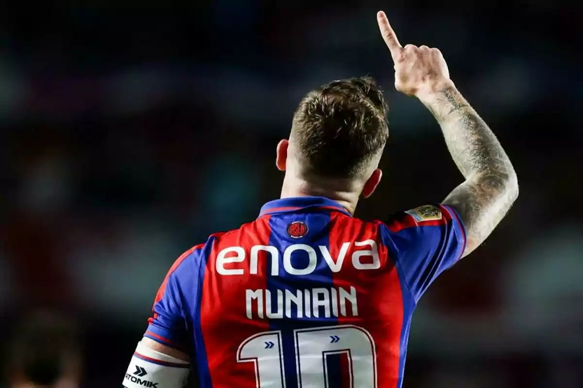 Futbolista con el dorsal 10 y el nombre Muniain en la camiseta levantando el brazo en señal de celebración Futbolista con el dorsal 10 y el nombre Muniain en la camiseta levantando el brazo en señal de celebración