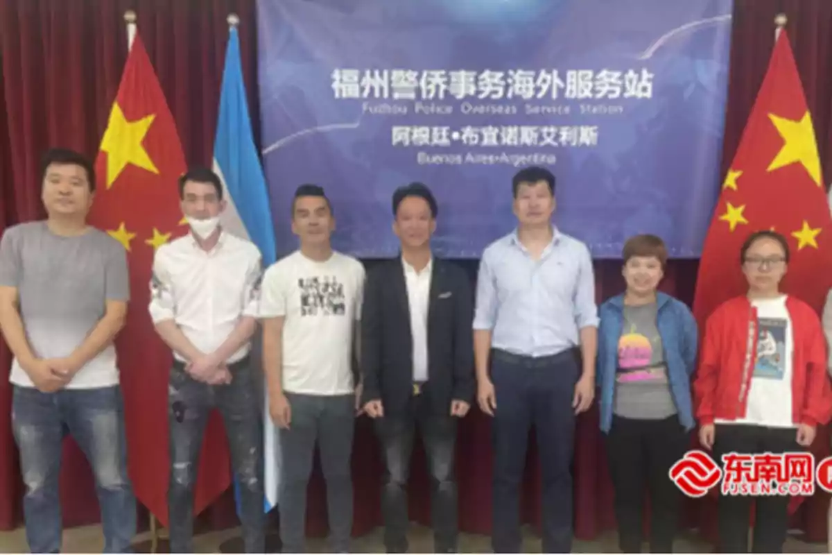 Un grupo de personas posando frente a banderas de China y Argentina con un cartel que dice 