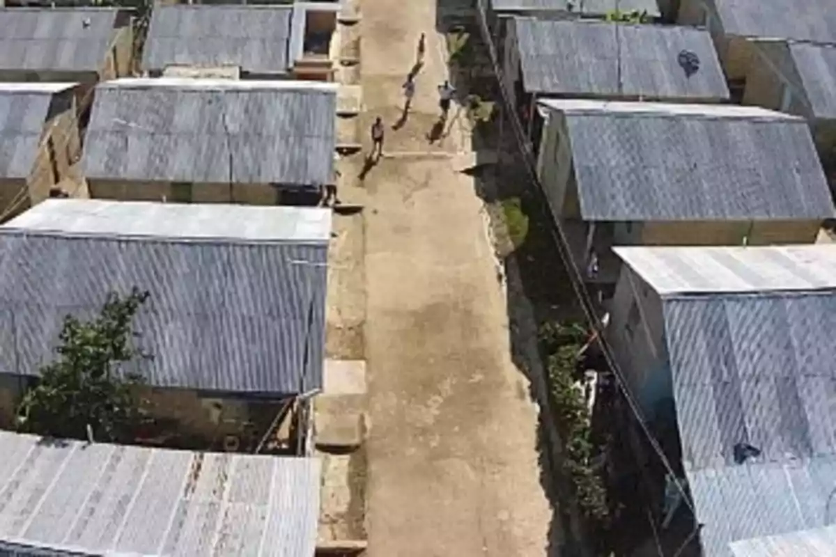 Vista aérea de un conjunto de casas con techos de lámina y una calle de tierra en el centro donde caminan algunas personas