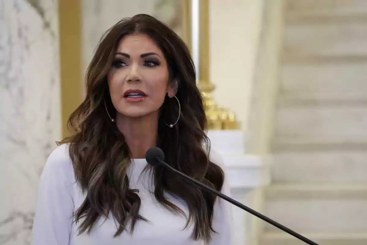 A woman speaking at a podium with a marble background and a staircase. A woman speaking at a podium with a marble background and a staircase.