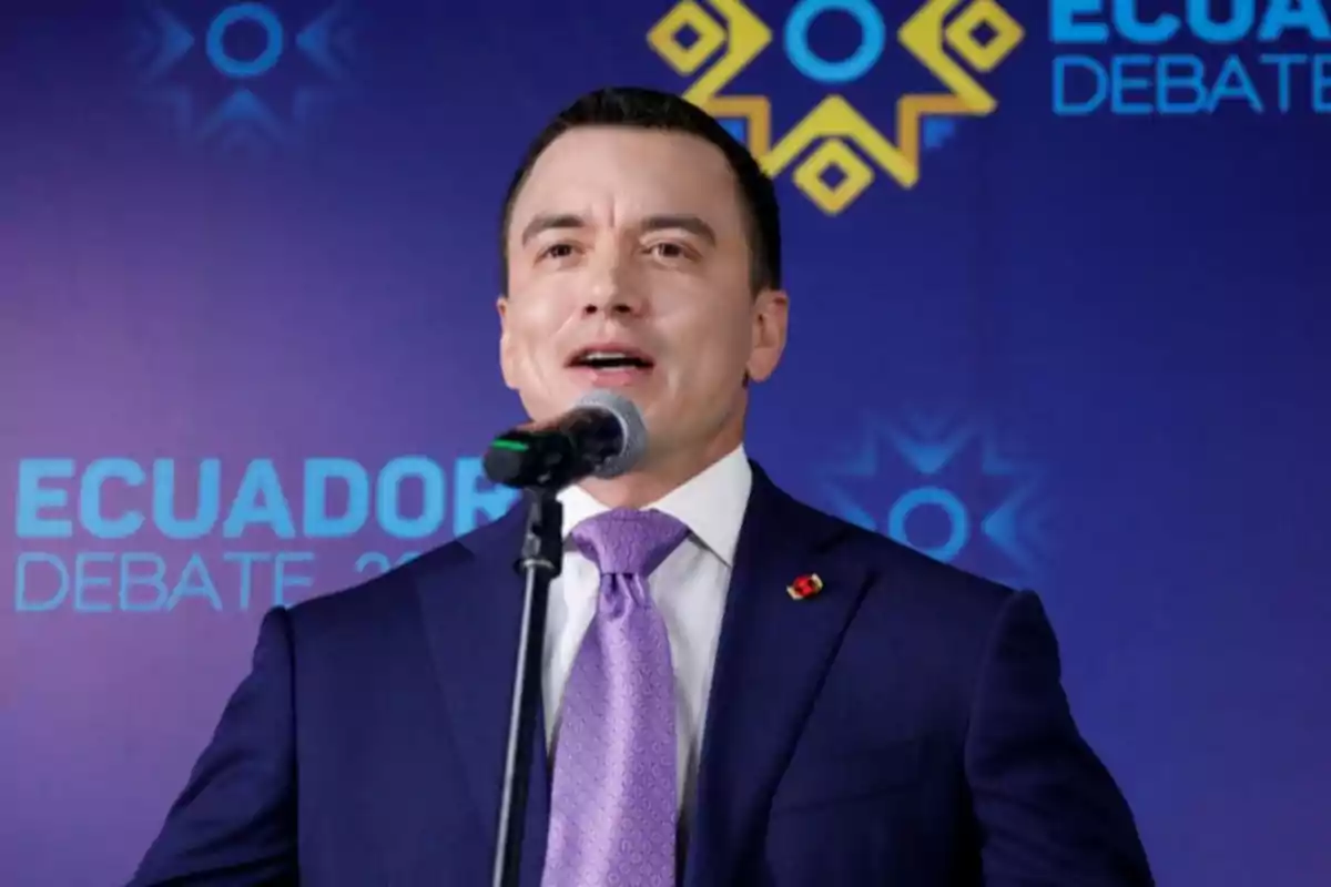 A man speaking into a microphone during a debate event in Ecuador.