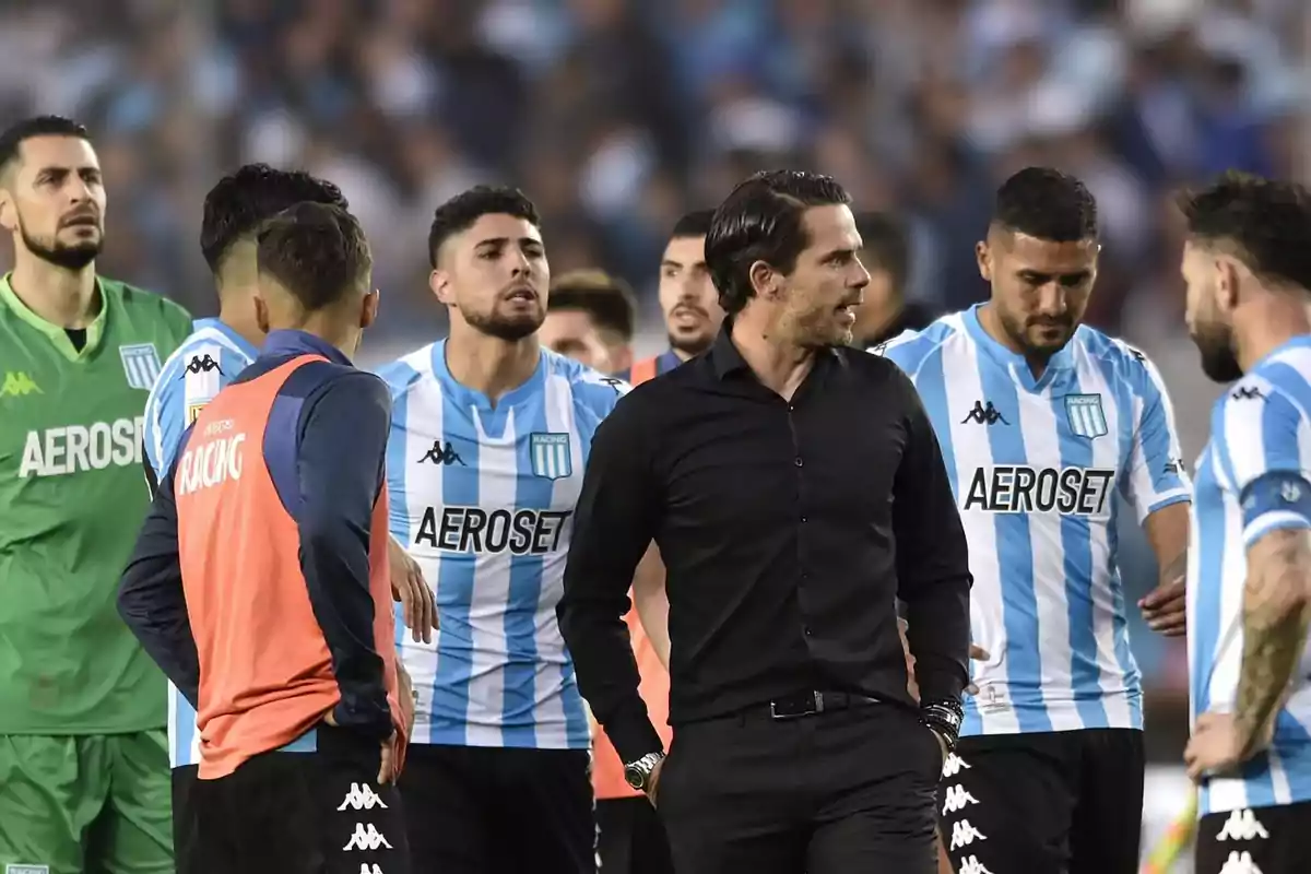Jugadores y cuerpo técnico de Racing Club en el campo de juego durante un partido de fútbol, luciendo camisetas celestes y blancas con el patrocinio de Aeroset. Jugadores y cuerpo técnico de Racing Club en el campo de juego durante un partido de fútbol, luciendo camisetas celestes y blancas con el patrocinio de Aeroset.