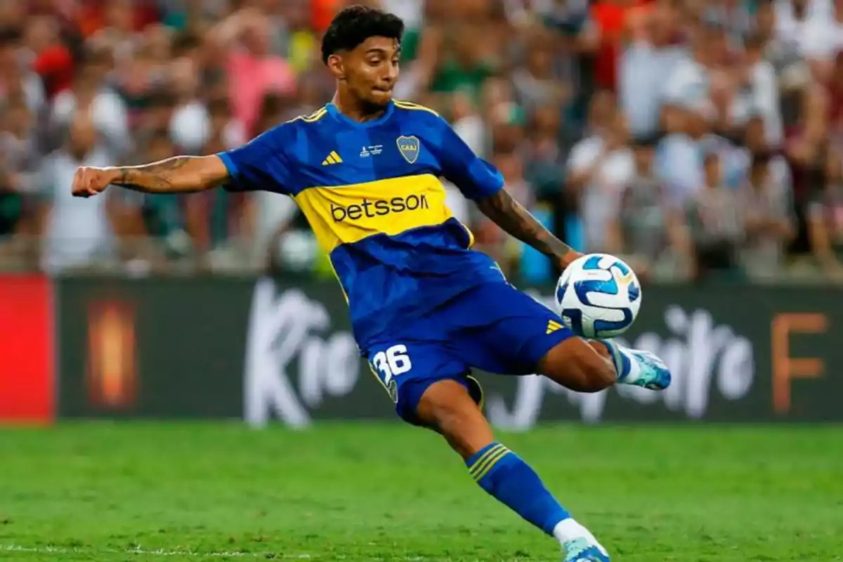 Jugador de fútbol con uniforme azul y amarillo controlando un balón en el campo.