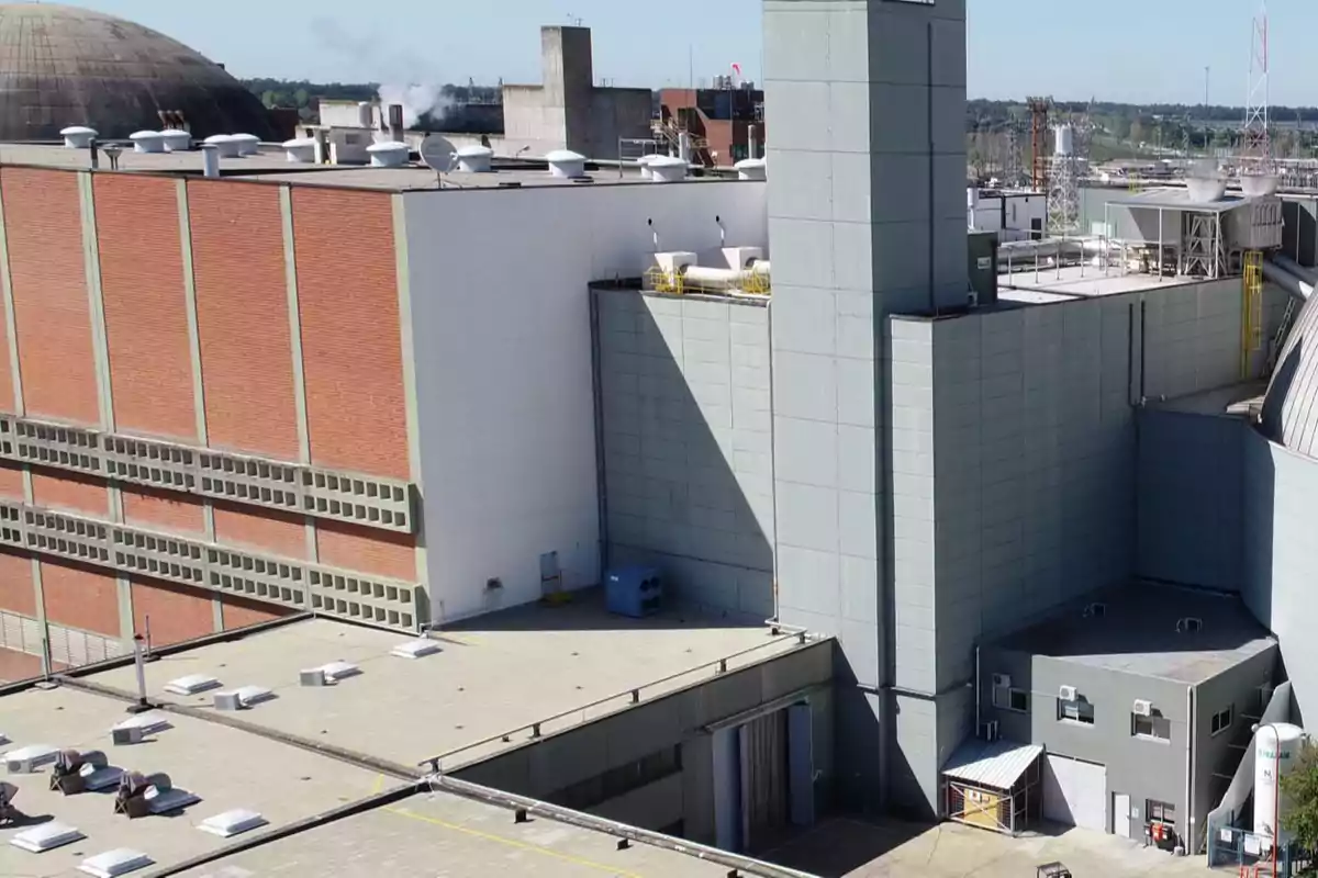 Vista de una planta industrial con edificios de ladrillo y concreto, techos planos y estructuras de ventilación en el techo.