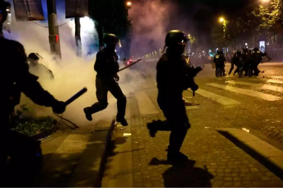 Riot police run down a smoke-filled street during a nighttime protest. Riot police run down a smoke-filled street during a nighttime protest.