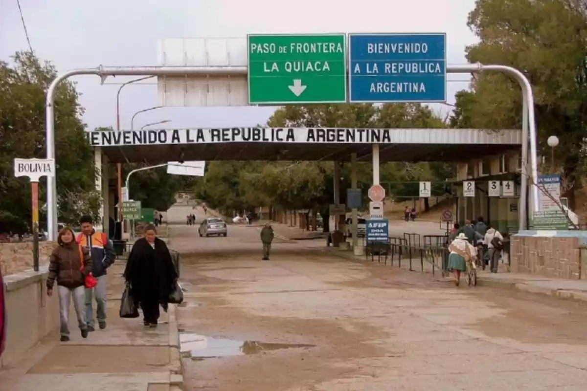 People crossing the border between Bolivia and Argentina at a border crossing with welcome signs and road signage People crossing the border between Bolivia and Argentina at a border crossing with welcome signs and road signage