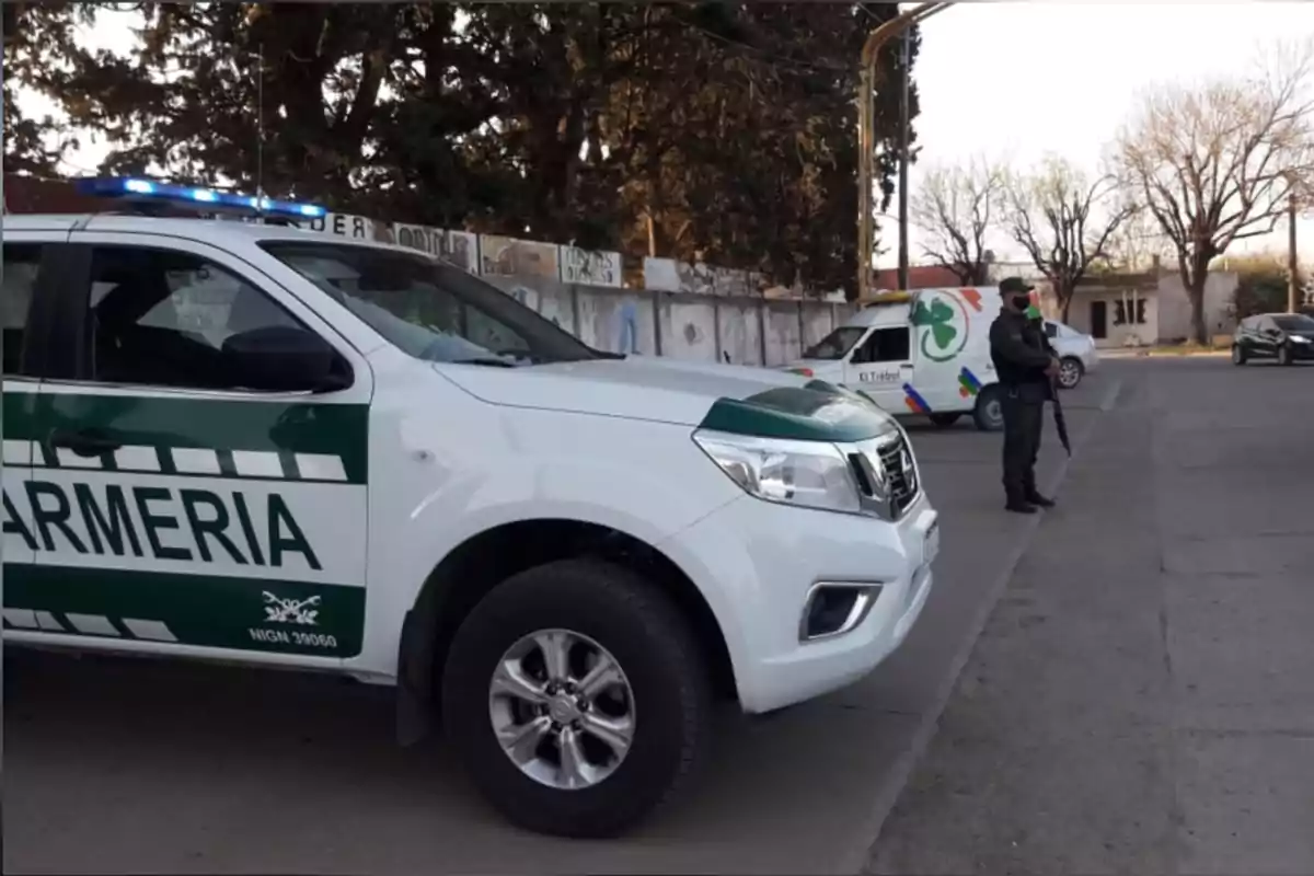 Gendarmerie patrol parked on the street with a uniformed officer standing and a white pickup truck in the background Gendarmerie patrol parked on the street with a uniformed officer standing and a white pickup truck in the background