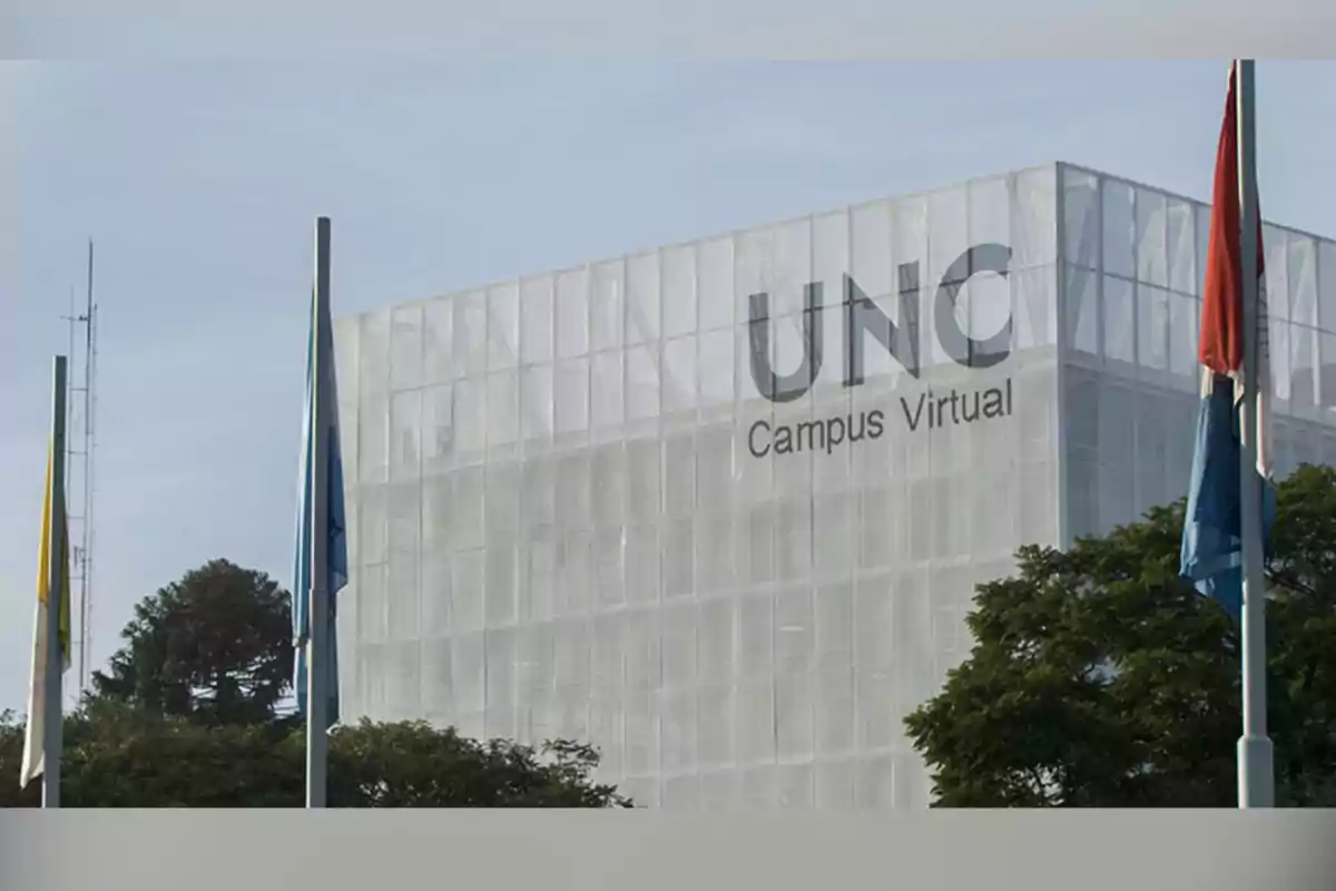 Edificio moderno de la UNC Campus Virtual rodeado de árboles y banderas Edificio moderno de la UNC Campus Virtual rodeado de árboles y banderas