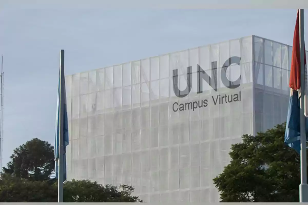 Edificio moderno de la UNC Campus Virtual rodeado de árboles y banderas Edificio moderno de la UNC Campus Virtual rodeado de árboles y banderas