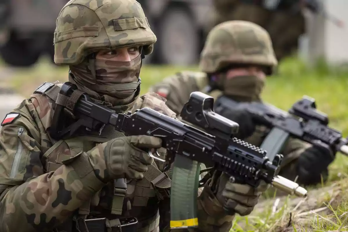 Soldados en uniforme de camuflaje con armas en posición de vigilancia en un entorno al aire libre.