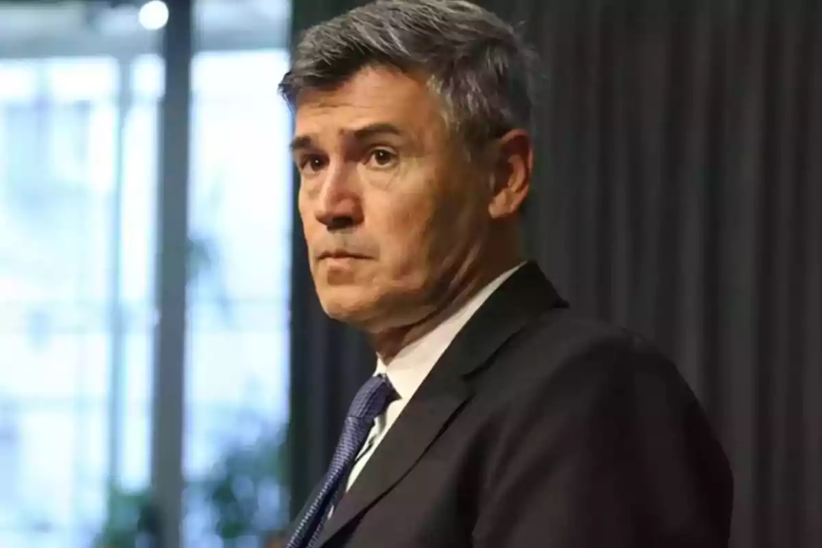 Gray-haired man in a dark suit and blue tie looking to the side in a professional indoor setting Gray-haired man in a dark suit and blue tie looking to the side in a professional indoor setting