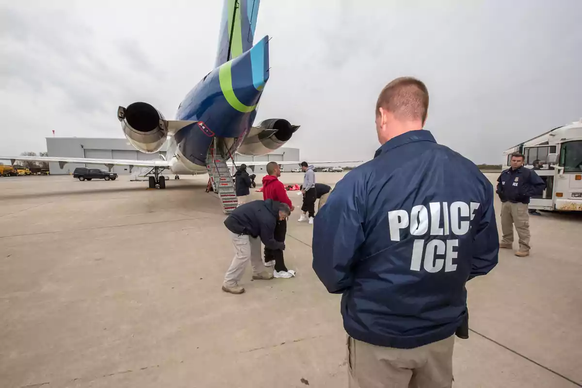 Agentes de ICE supervisan a personas subiendo a un avión en una pista de aeropuerto.