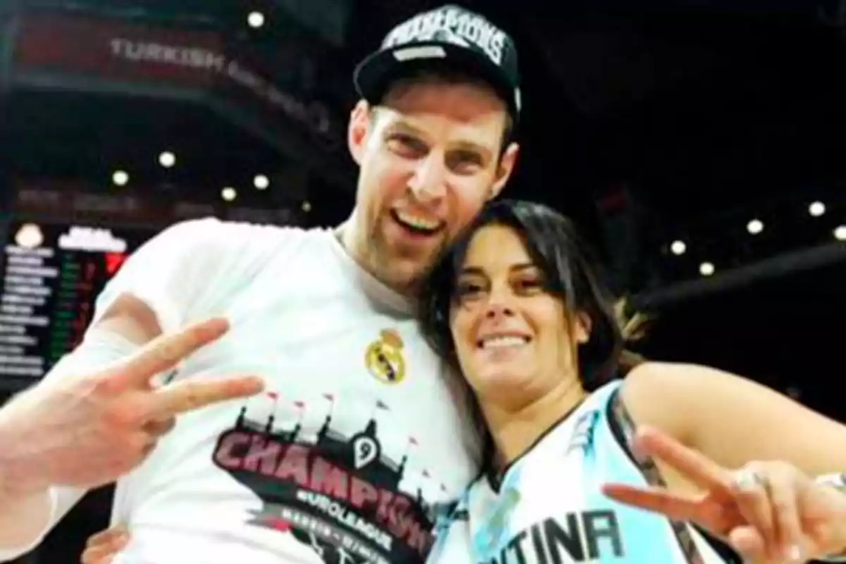 Two smiling people pose for a photo at a sporting event, both making the peace sign with their fingers. Two smiling people pose for a photo at a sporting event, both making the peace sign with their fingers.