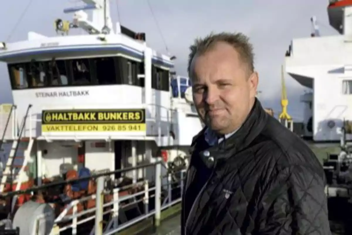 A man standing in front of a ship with a sign that says A man standing in front of a ship with a sign that says