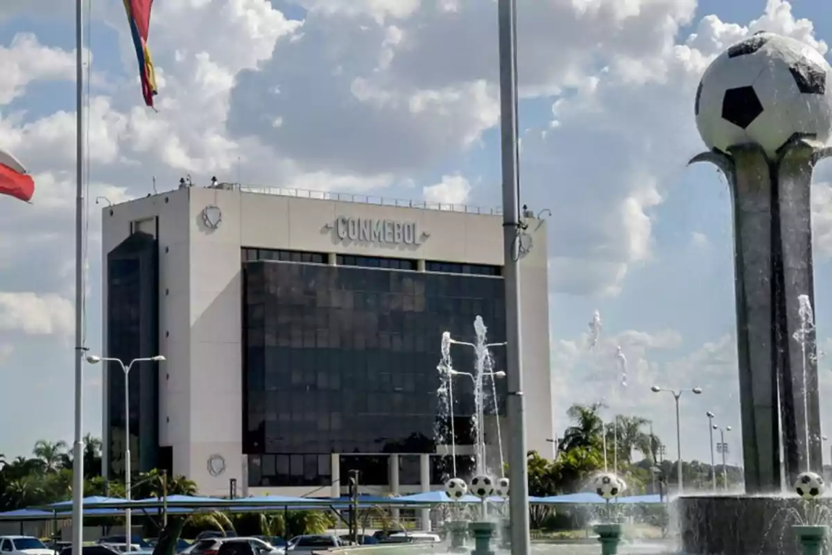 CONMEBOL building with a fountain decorated with soccer balls and flags waving in front. CONMEBOL building with a fountain decorated with soccer balls and flags waving in front.