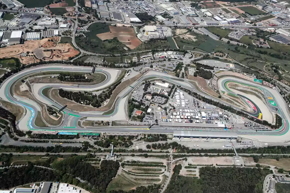 Aerial view of a racetrack with multiple curves surrounded by green areas and buildings. Aerial view of a racetrack with multiple curves surrounded by green areas and buildings.