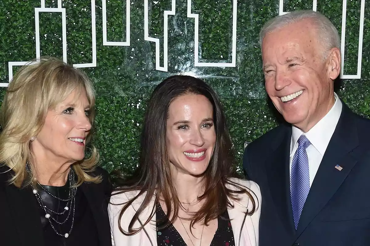 Three people smile in front of a background of green leaves and a white line design.