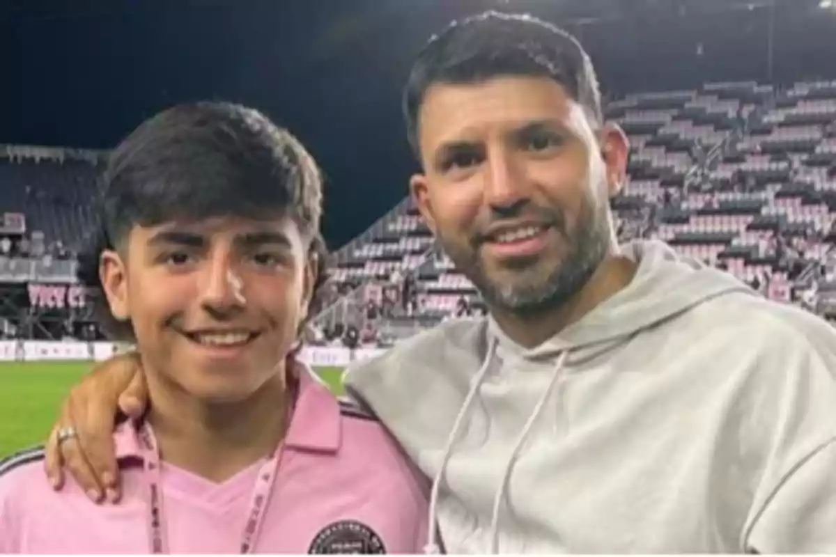 Two people smile while posing together in a soccer stadium. Two people smile while posing together in a soccer stadium.