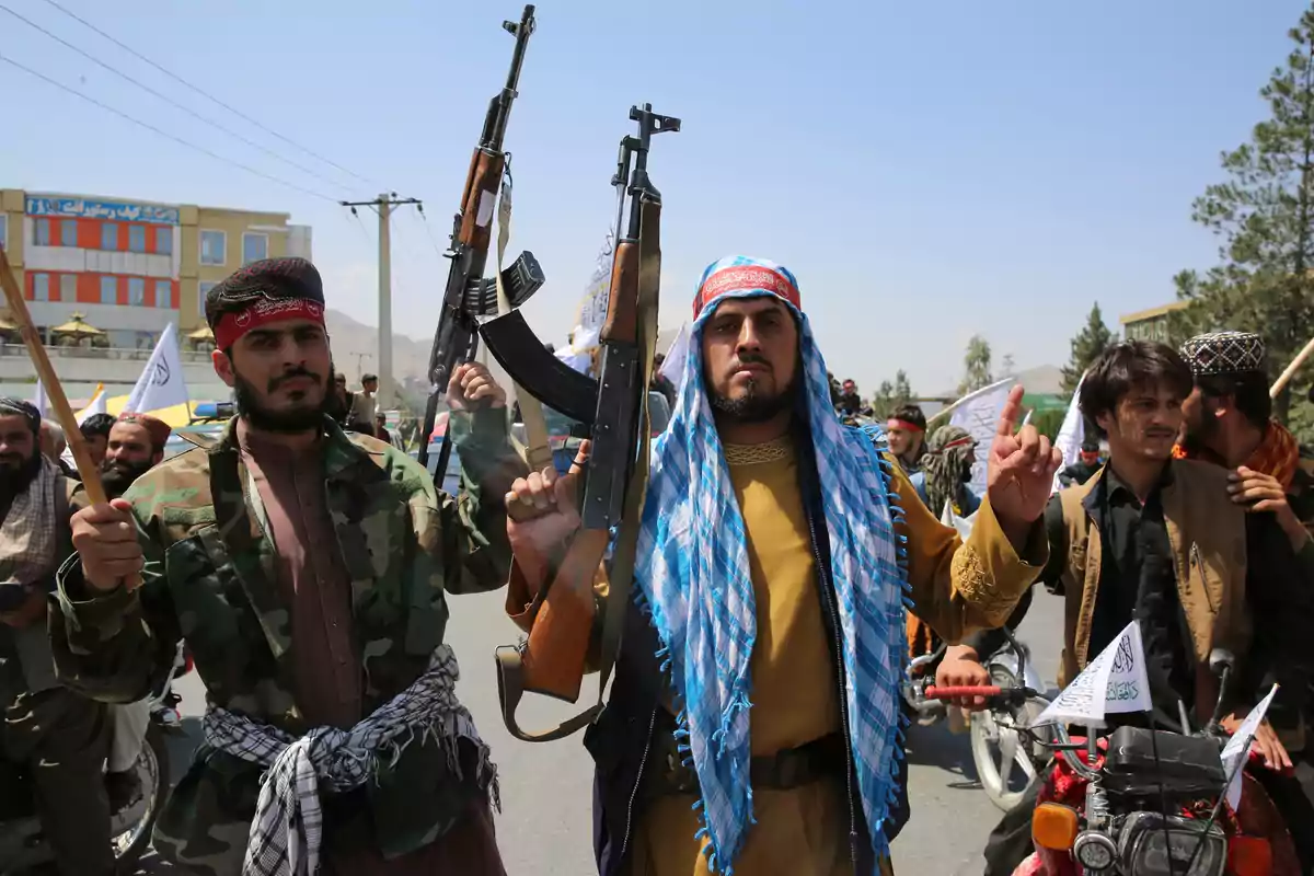 Group of armed men with rifles and traditional clothing marching down a street during the day