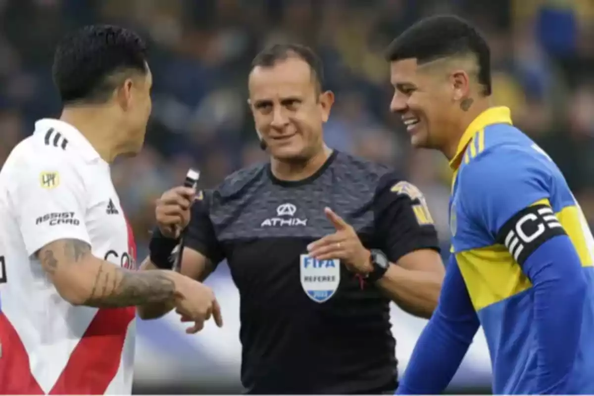 A referee talks and smiles with the captains of River Plate and Boca Juniors before a soccer match. A referee talks and smiles with the captains of River Plate and Boca Juniors before a soccer match.