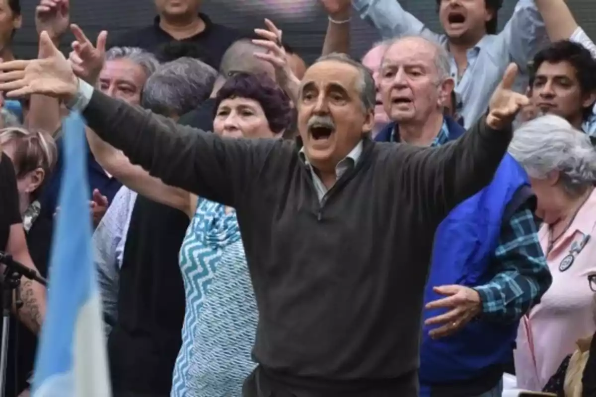 Un hombre con los brazos extendidos en medio de una multitud que parece estar animada.