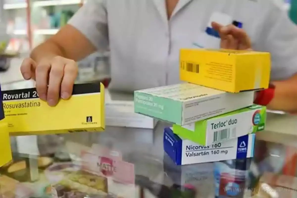 Persona organizando cajas de medicamentos en un mostrador de farmacia.