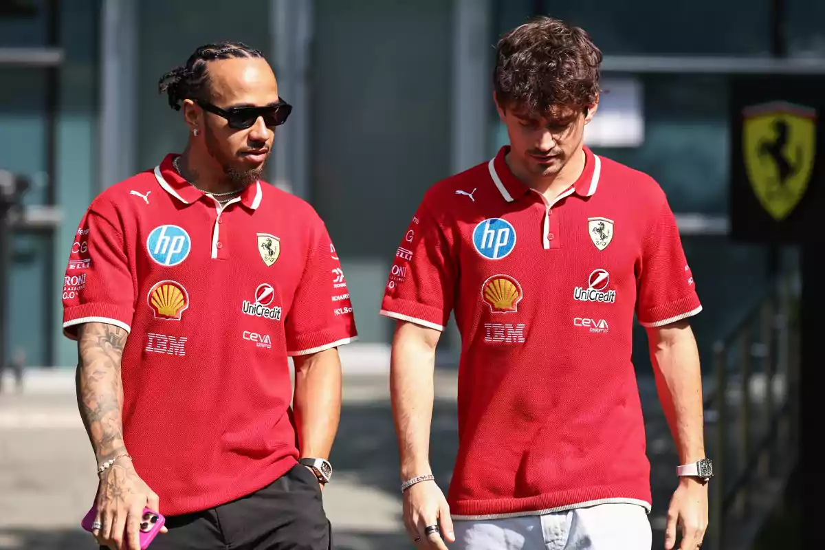 Dos personas caminando con camisetas rojas de Ferrari llenas de logotipos de patrocinadores. Dos personas caminando con camisetas rojas de Ferrari llenas de logotipos de patrocinadores.