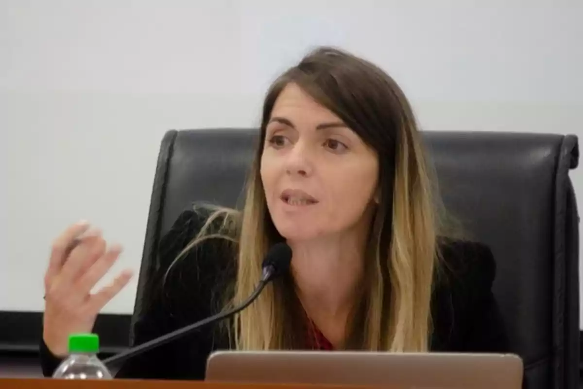 Una mujer hablando en un micrófono durante una conferencia o reunión.