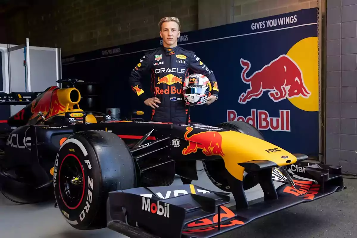 Un piloto de carreras con su uniforme de Red Bull está de pie junto a un auto de Fórmula 1 en un garaje. Un piloto de carreras con su uniforme de Red Bull está de pie junto a un auto de Fórmula 1 en un garaje.