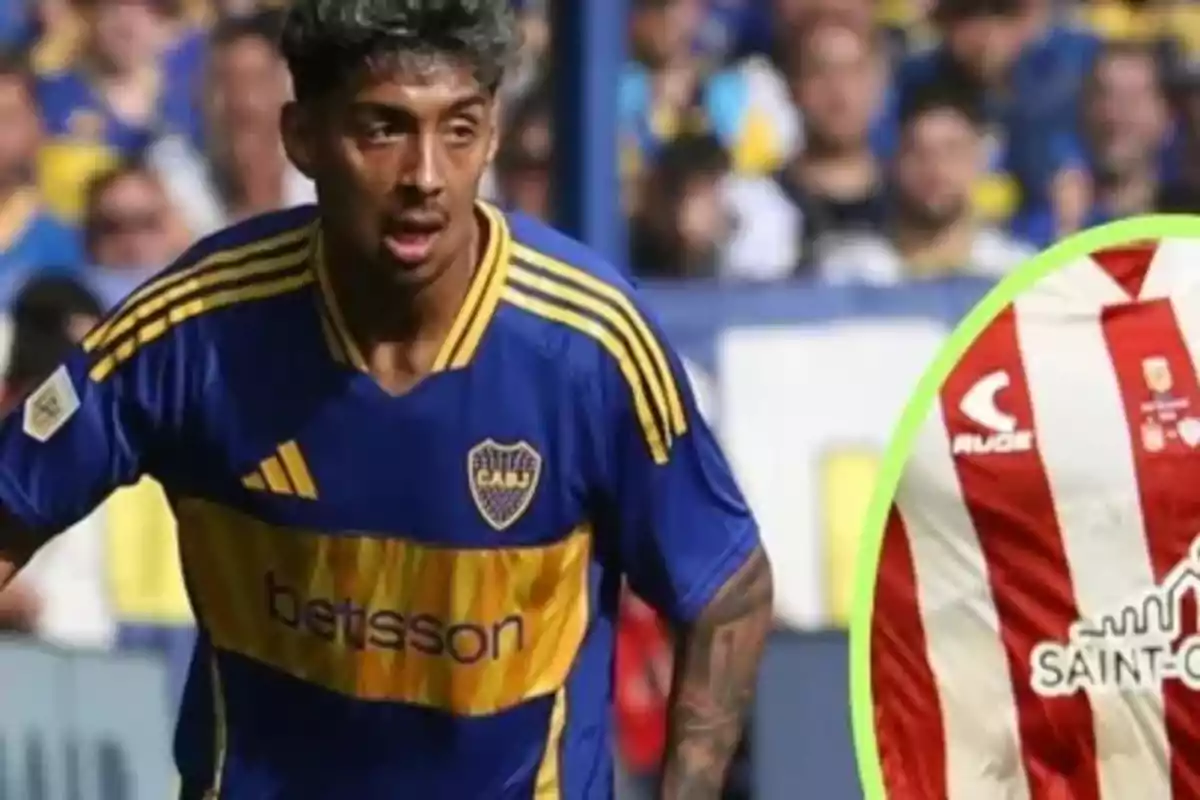 Jugador de fútbol con camiseta azul y amarilla en un partido, con fondo de público y parte de otra camiseta a rayas rojas y blancas.