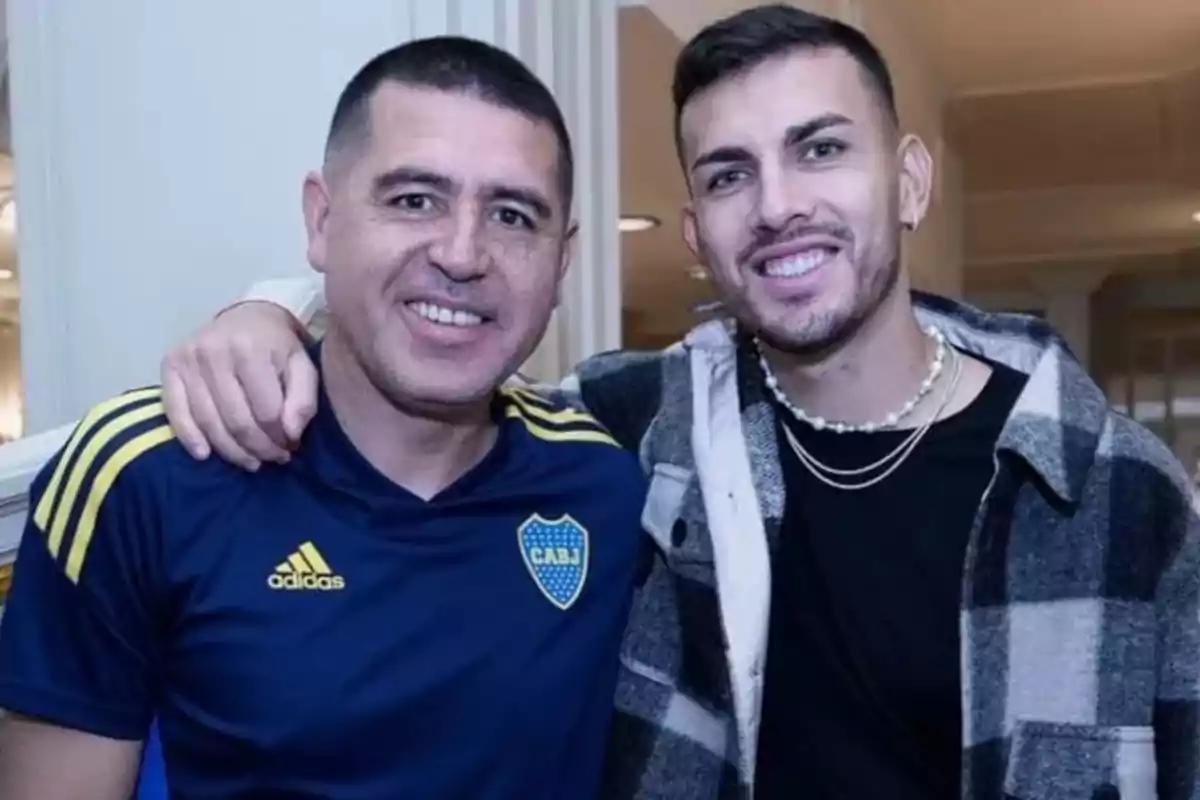 Dos personas sonriendo, una con camiseta de Boca Juniors y la otra con una chaqueta a cuadros.