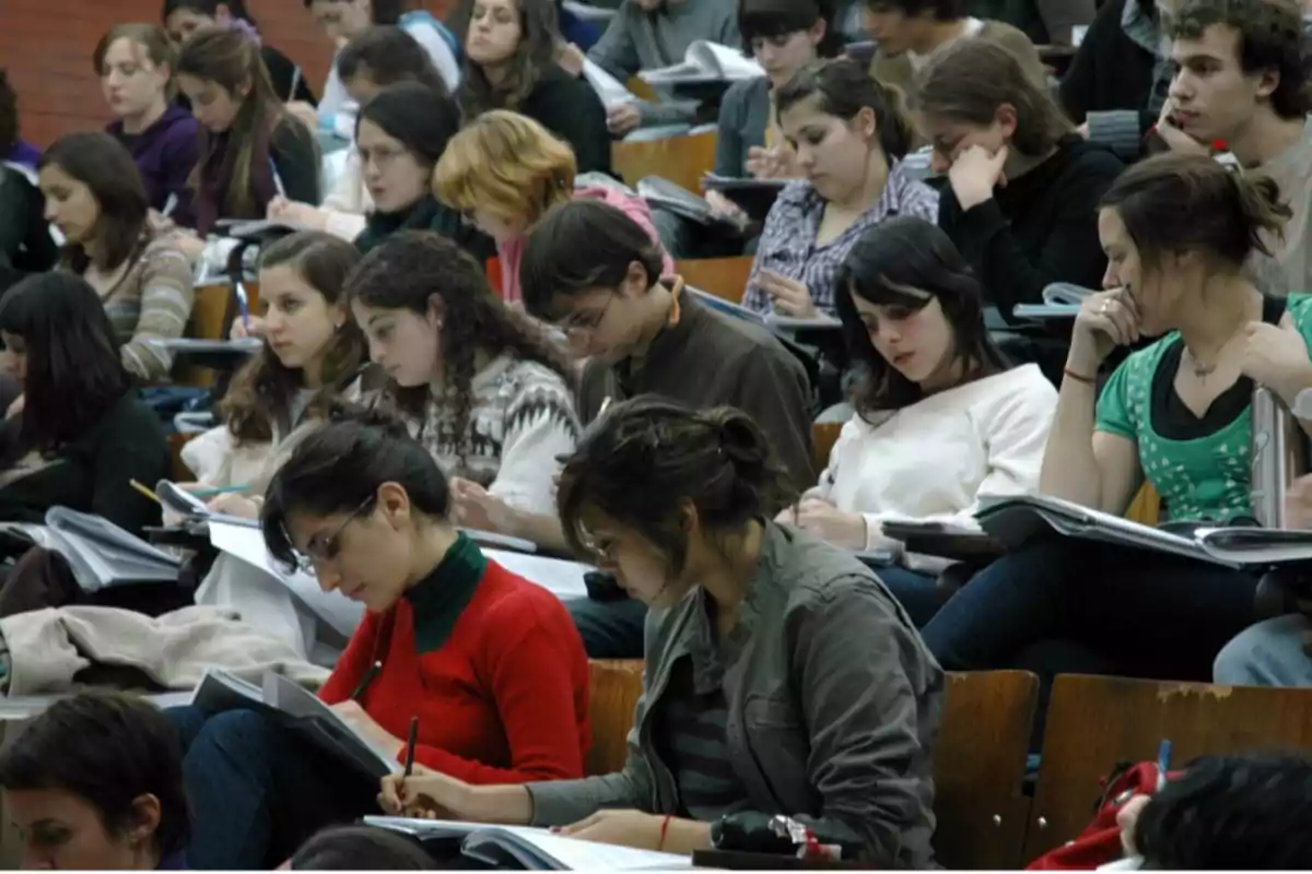 Estudiantes tomando apuntes en un aula universitaria.