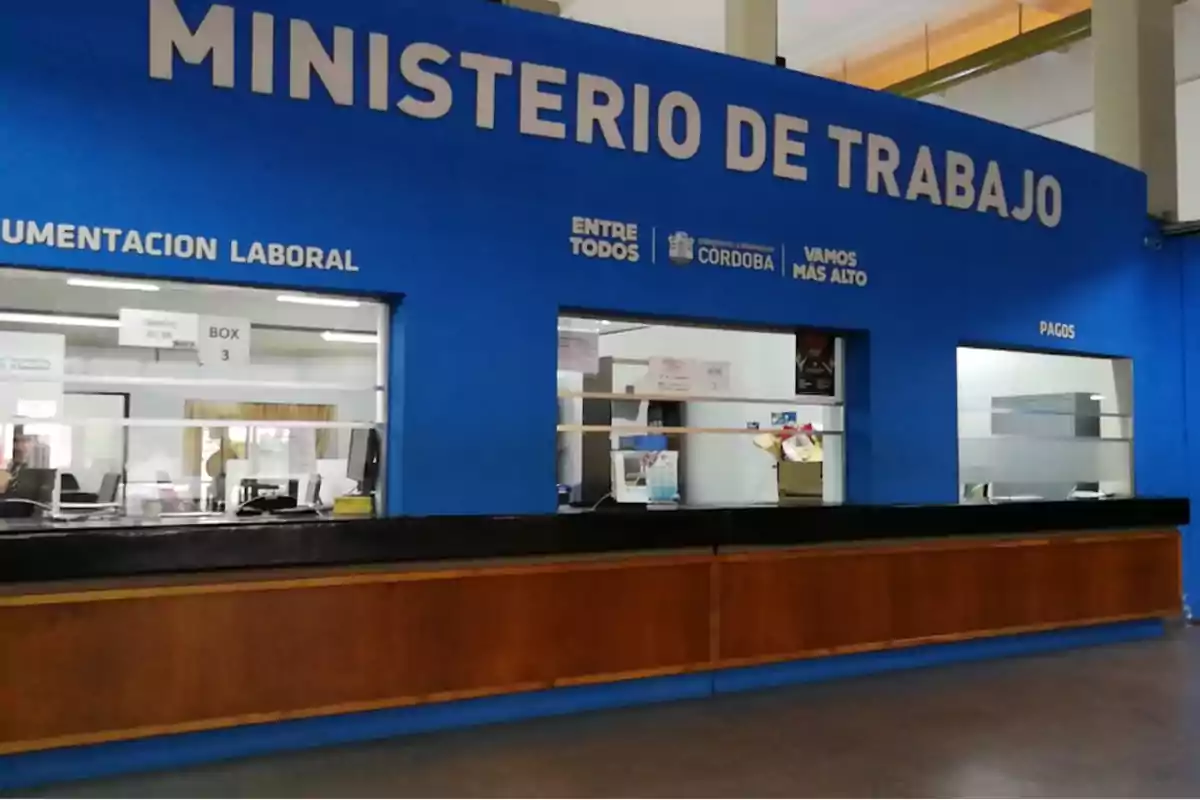 Mostrador de atención al público en el Ministerio de Trabajo con letreros de documentación laboral y pagos.