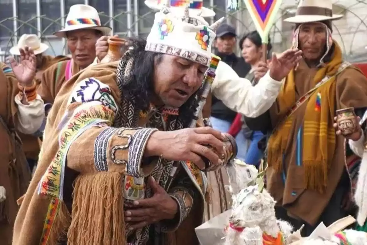 A group of people participates in a traditional Andean ceremony, with colorful clothing and ritual elements.