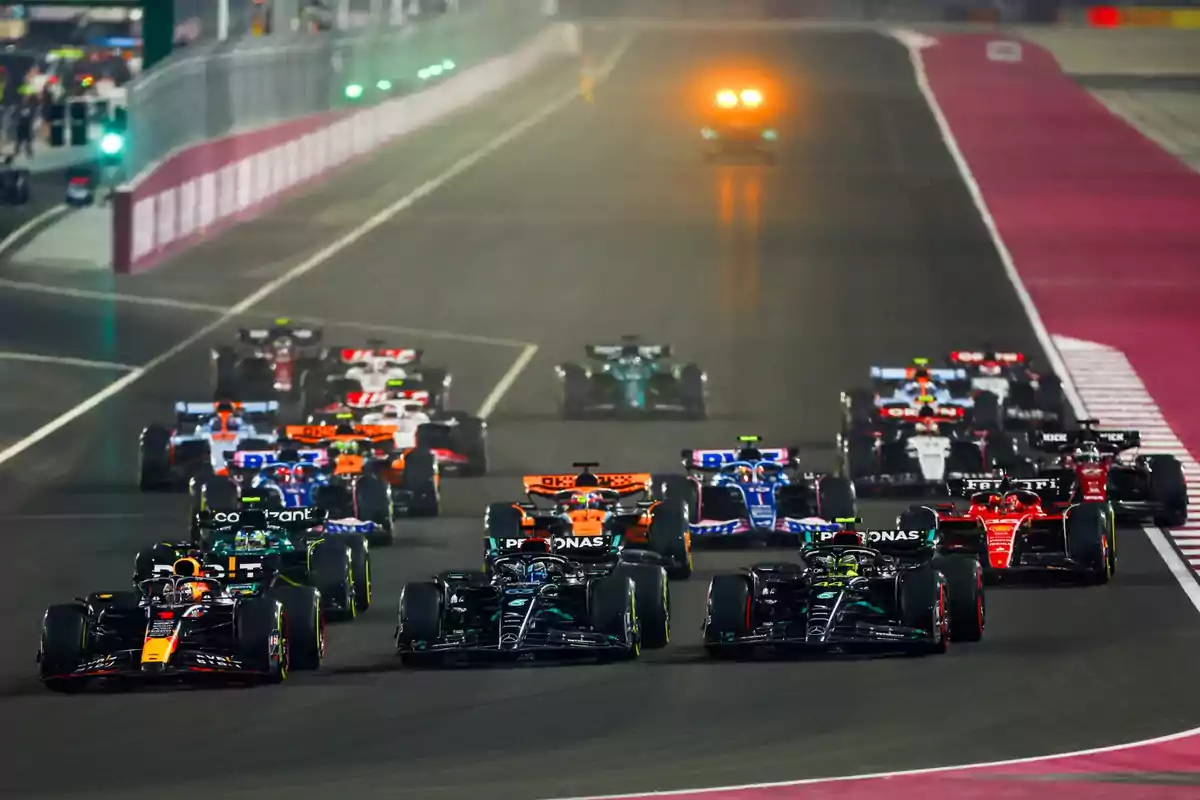 Carrera de Fórmula 1 con varios autos compitiendo en una pista iluminada.