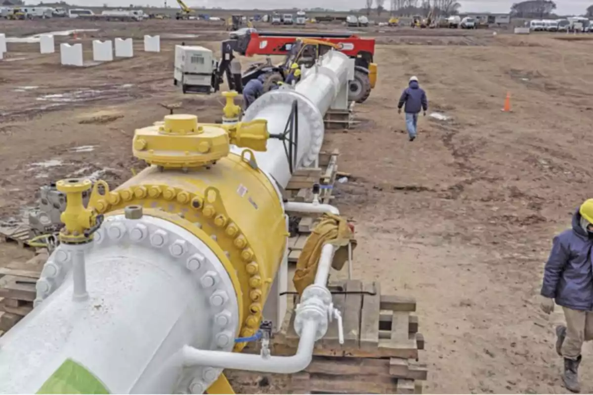 Workers at a construction site installing a large pipe in an open field. Workers at a construction site installing a large pipe in an open field.
