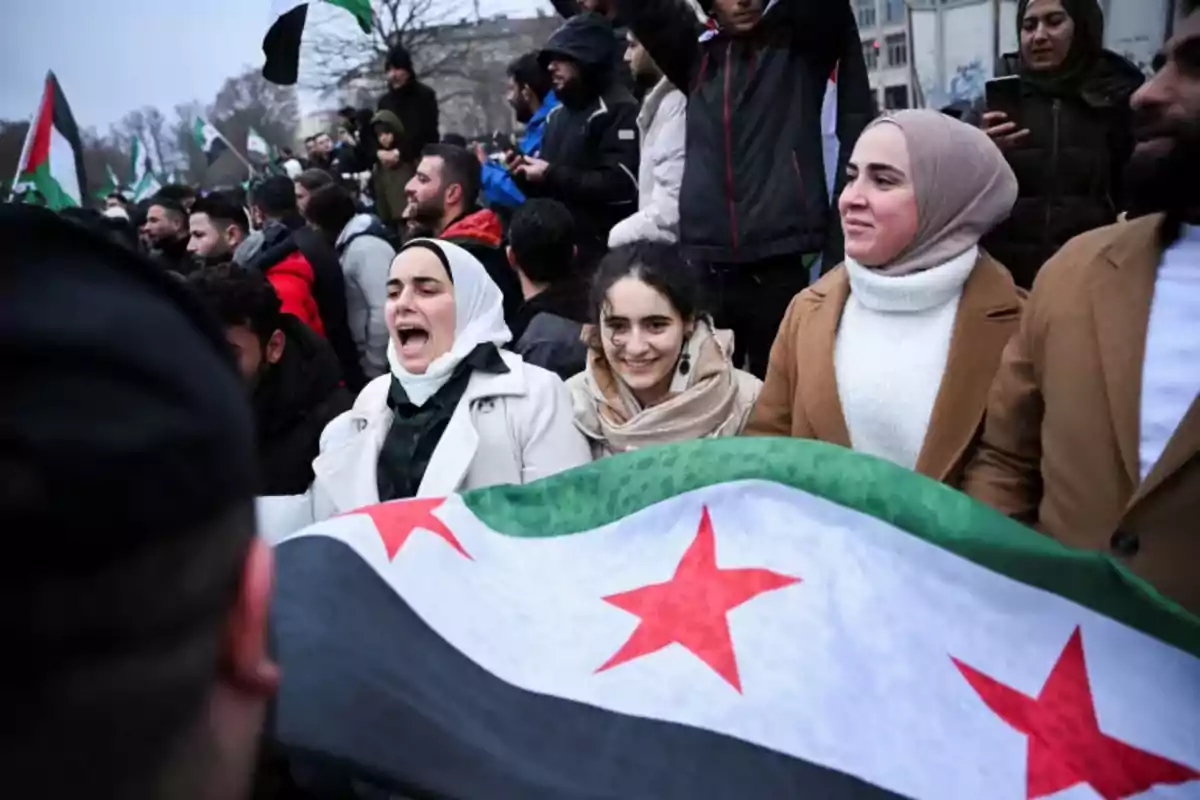 Un grupo de personas participa en una manifestación sosteniendo una bandera con estrellas rojas.