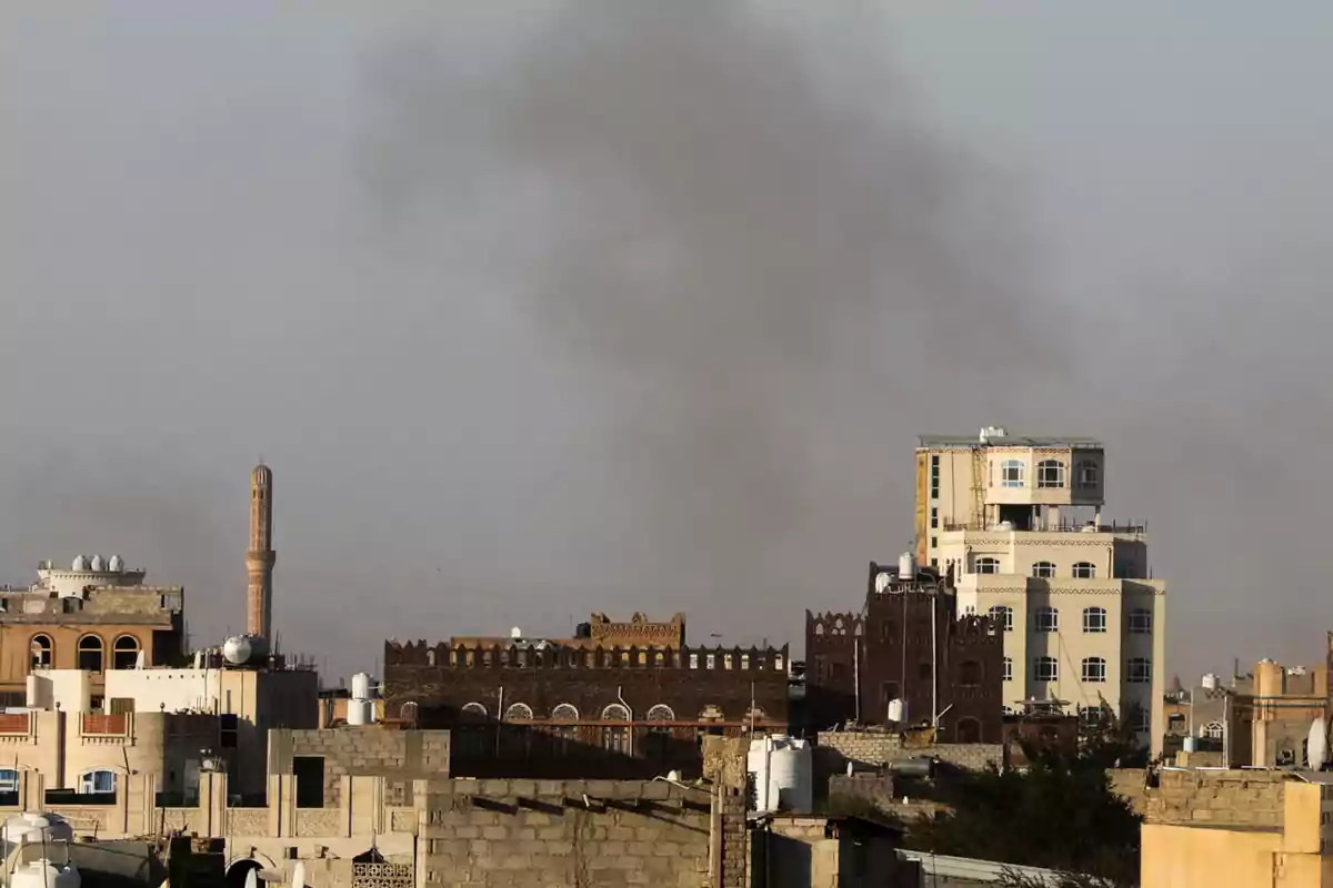 Edificios tradicionales y modernos se alzan bajo un cielo gris con humo en el horizonte.
