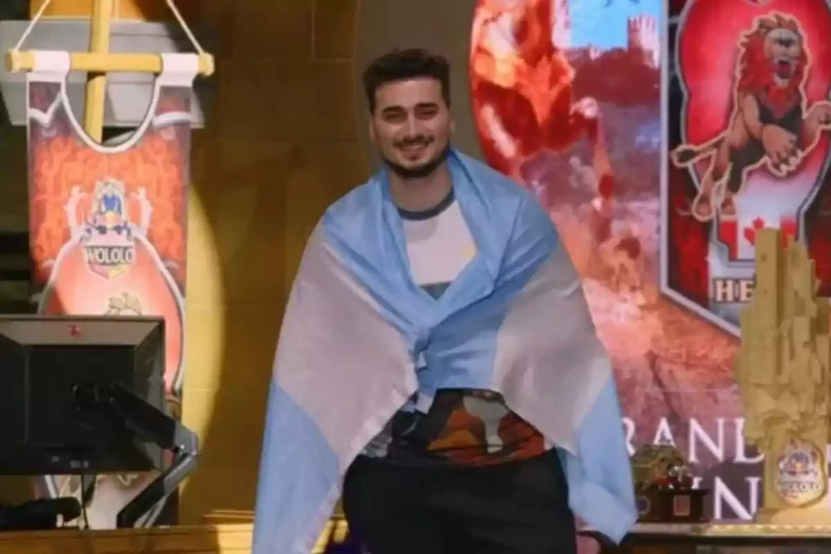 Un hombre sonriente con una bandera argentina sobre los hombros en un evento de videojuegos.