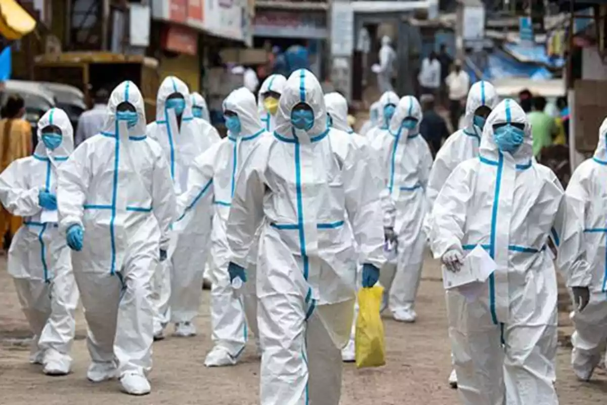 Un grupo de personas con trajes de protección blanca y azul camina por una calle.