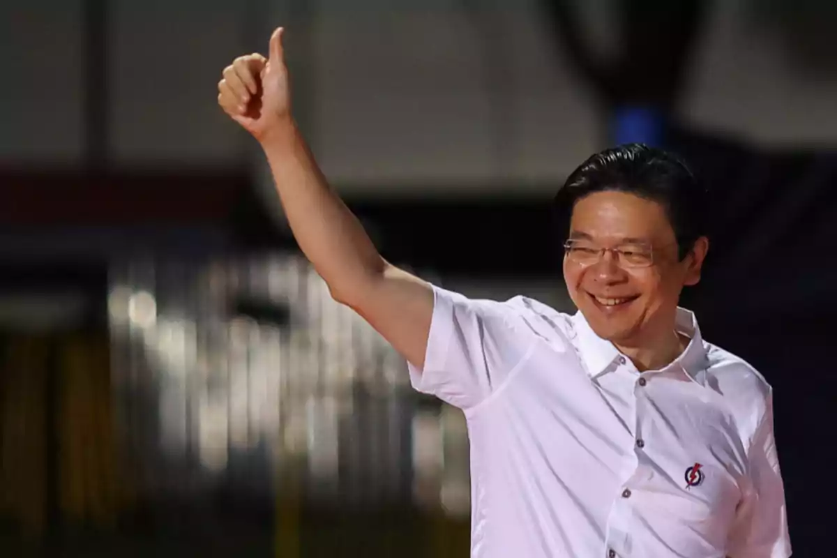 A man in a white jersey smiles and gives a thumbs up.