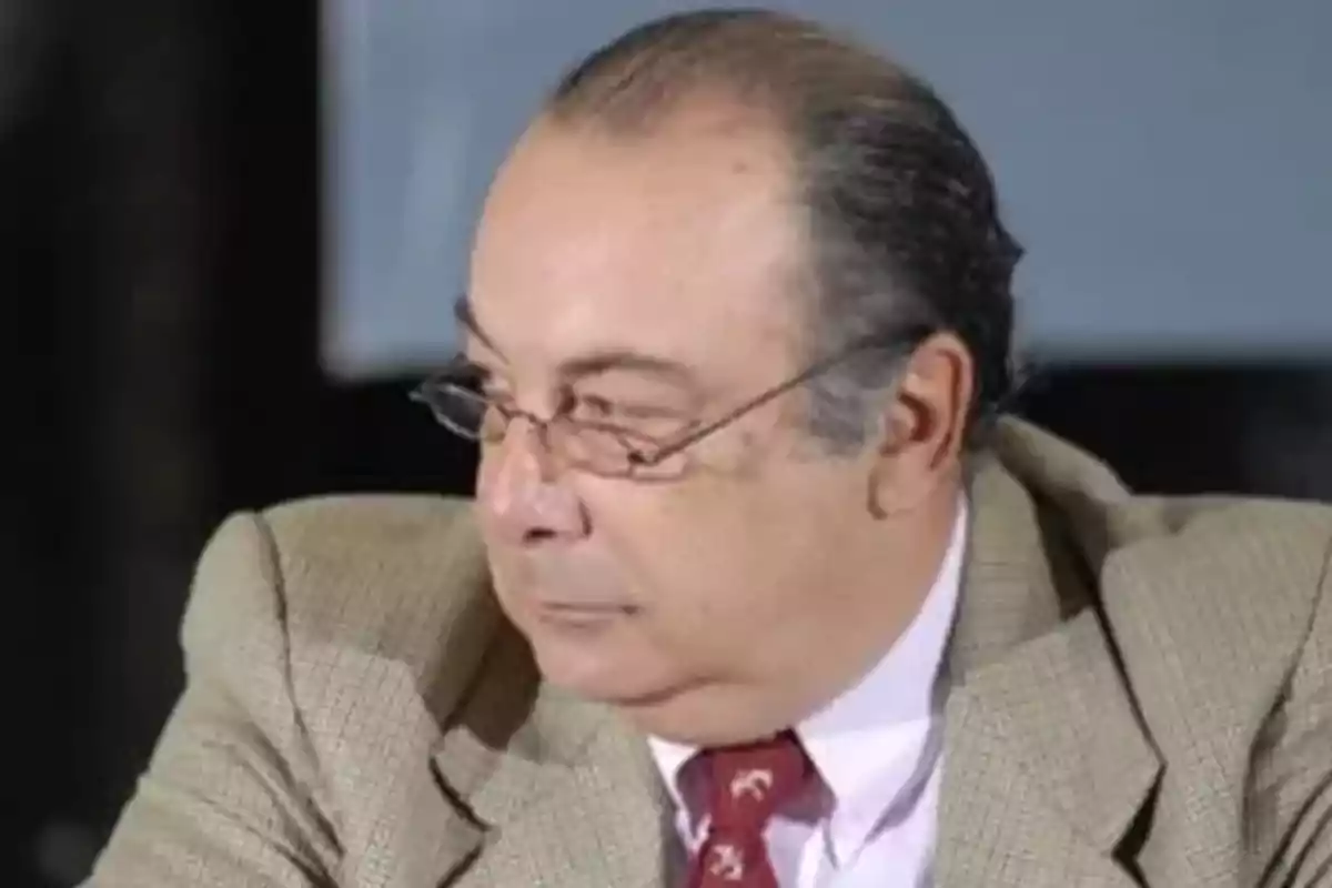 Hombre de mediana edad con gafas y traje beige mirando hacia un lado Hombre de mediana edad con gafas y traje beige mirando hacia un lado