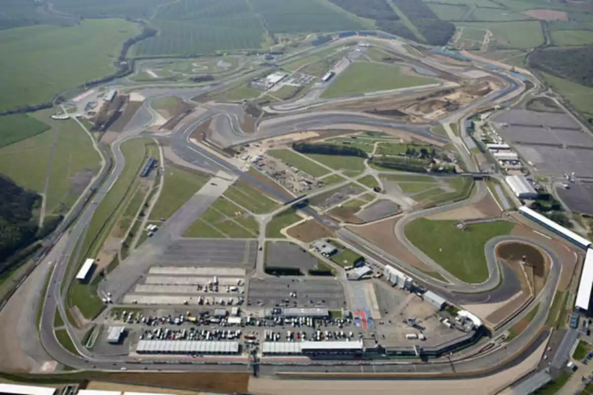 Aerial view of a racetrack surrounded by green areas and auxiliary buildings Aerial view of a racetrack surrounded by green areas and auxiliary buildings