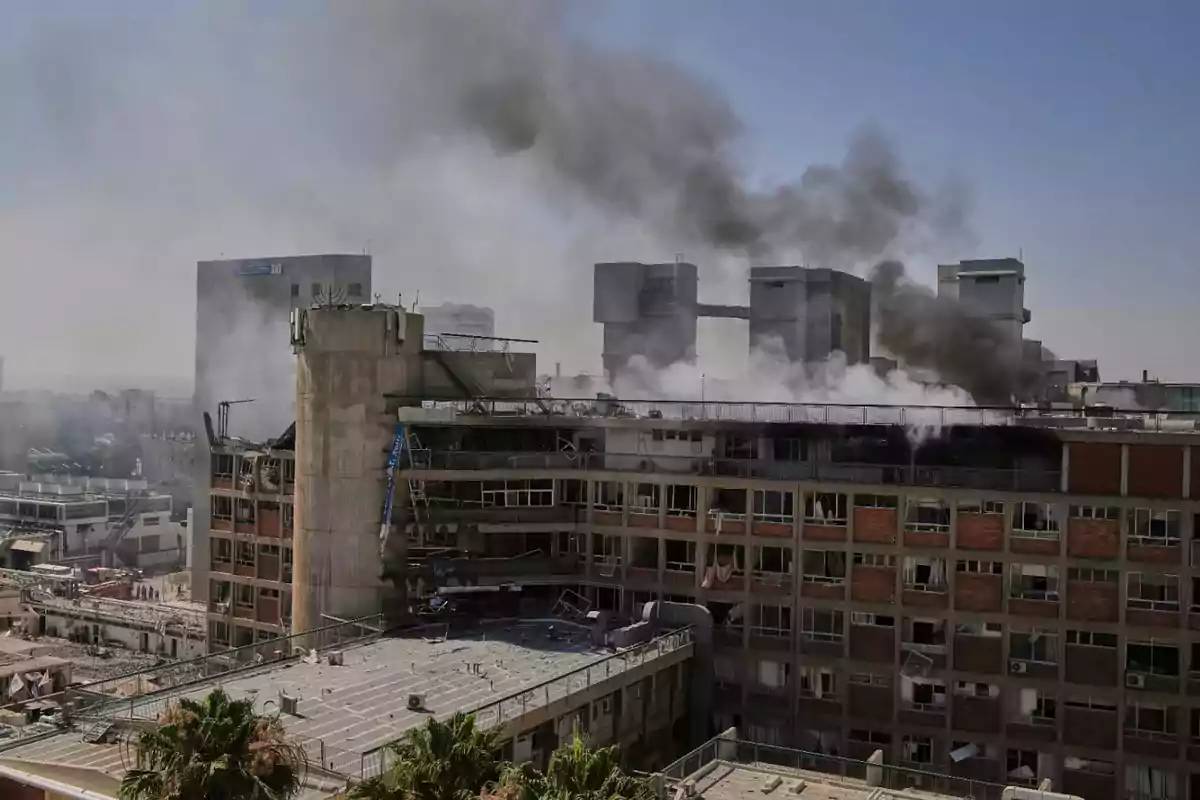 Large building with broken windows and black smoke coming out of the roof in a city