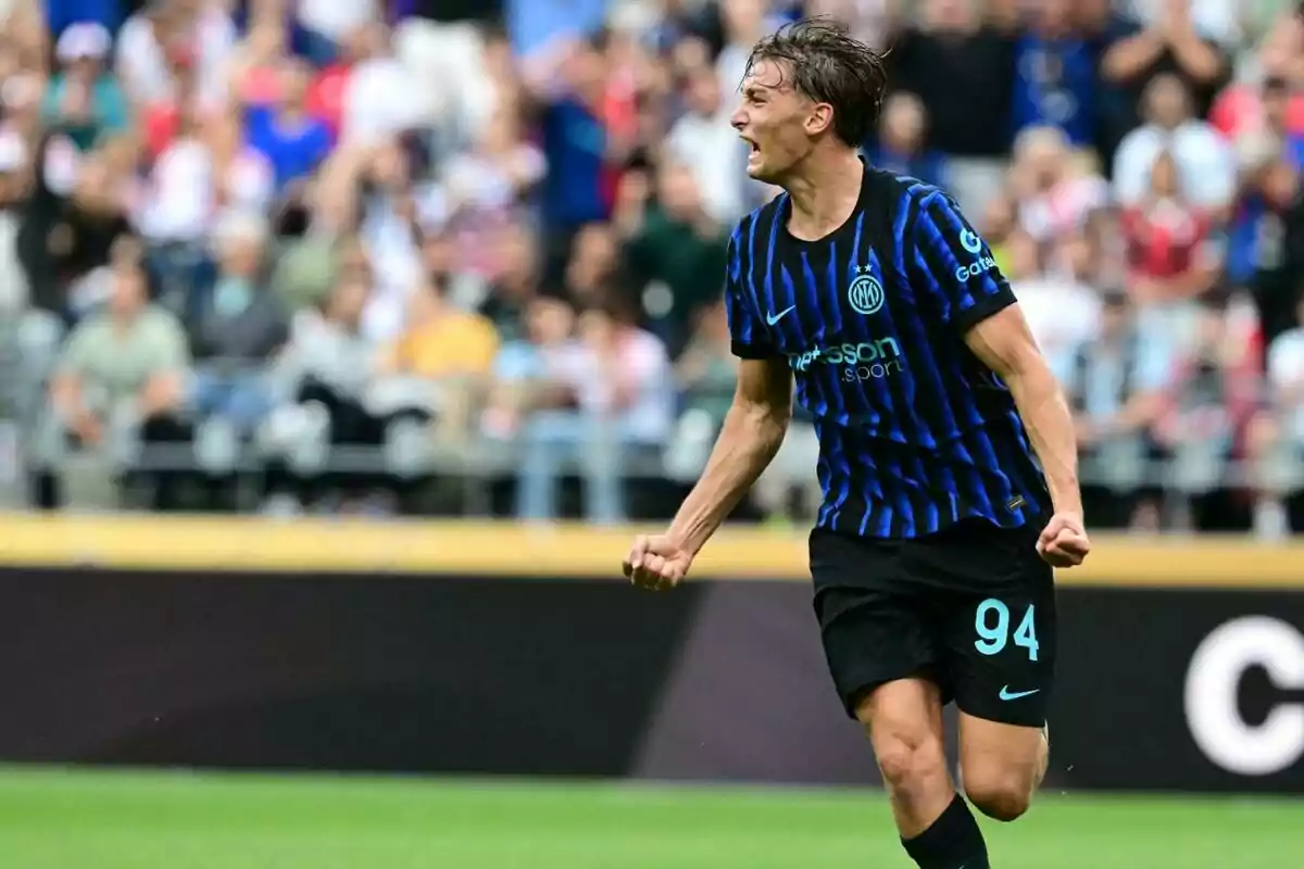 Futbolista del Inter de Milán celebrando un gol en el campo con aficionados de fondo