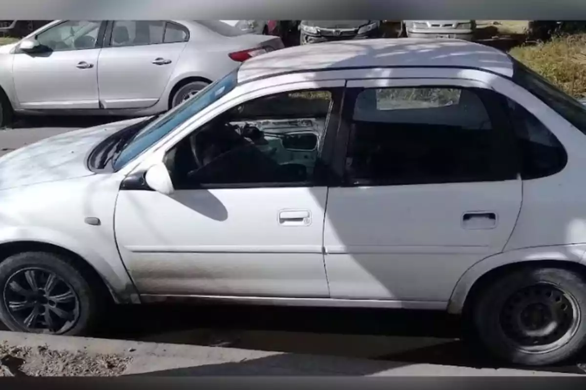 Auto compacto blanco estacionado en la calle con la puerta del conductor sin panel interior y llantas de diferente diseño Auto compacto blanco estacionado en la calle con la puerta del conductor sin panel interior y llantas de diferente diseño