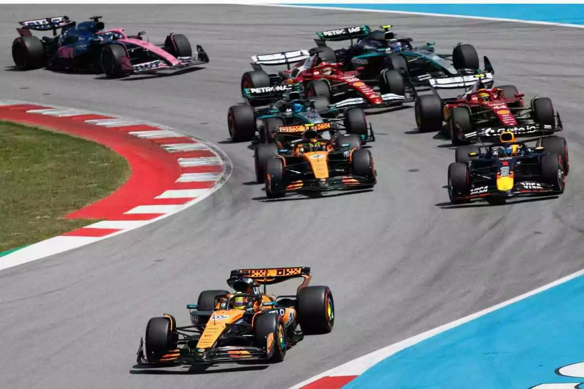 Several Formula 1 cars race through a corner on a track during a race.